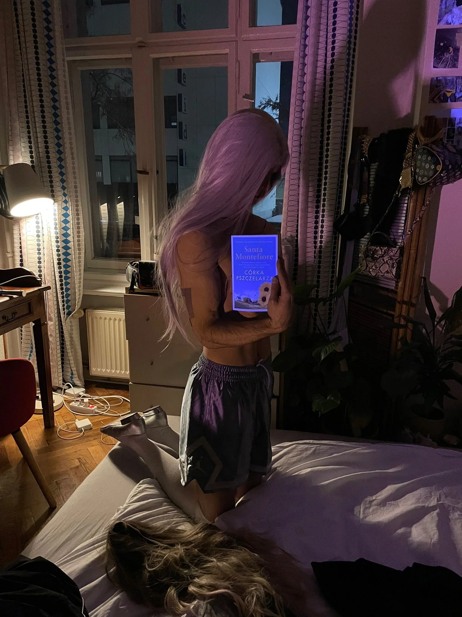 Ave Vanilla - Interior Study: A figure with lavender hair kneeling on a bed, holding a glowing book titled "The Beekeeper's Daughter" in a dimly lit room with purple neon highlights.