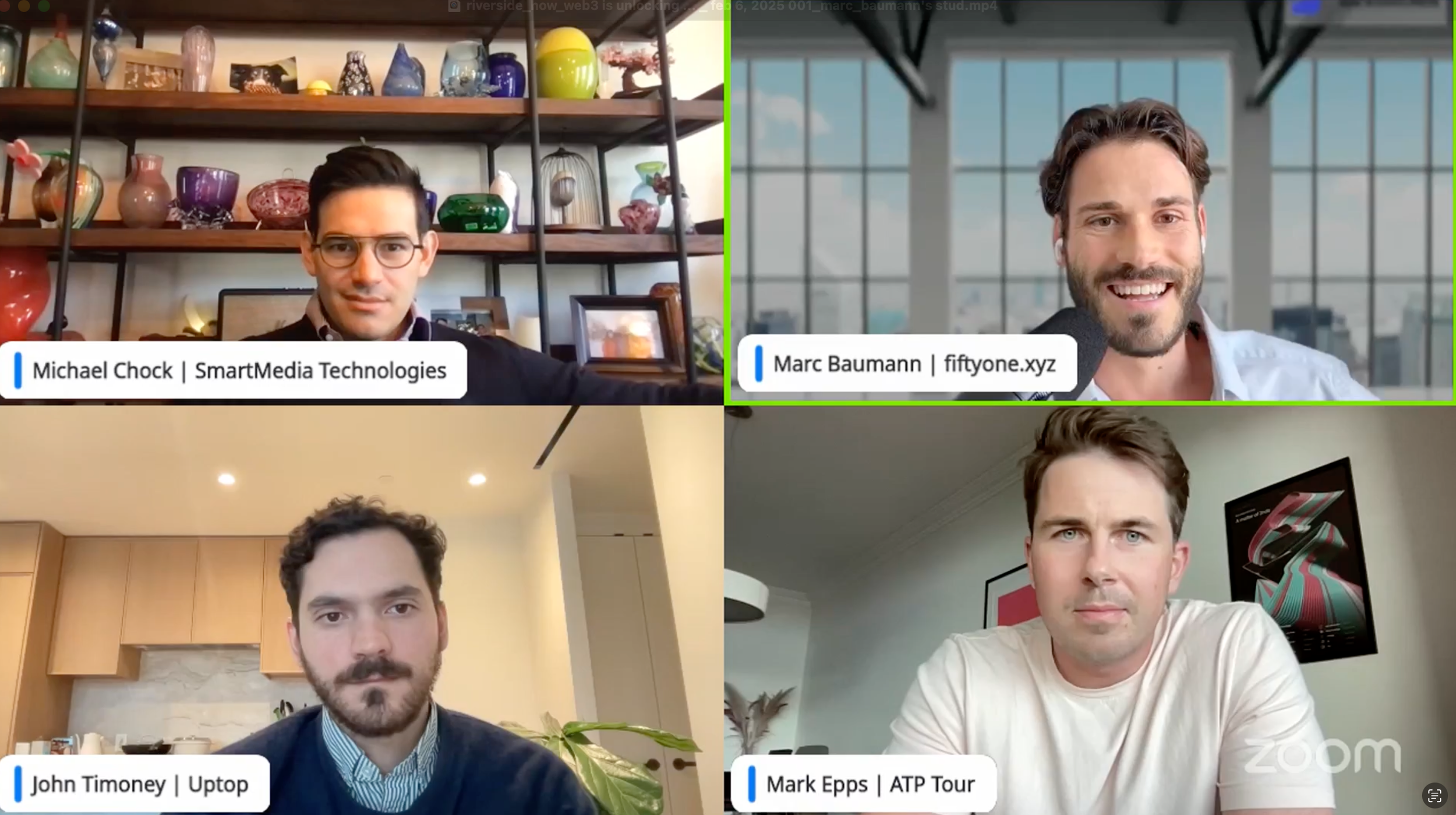 Four men in a virtual meeting, each in individual video call windows. Background varies: one with a shelf of colorful glassware, another with large windows, one in a modern kitchen, and the last with framed artwork. Name tags identify as Michael Chock, Marc Baumann, John Timoney, and Mark Epps. The Zoom logo is present.