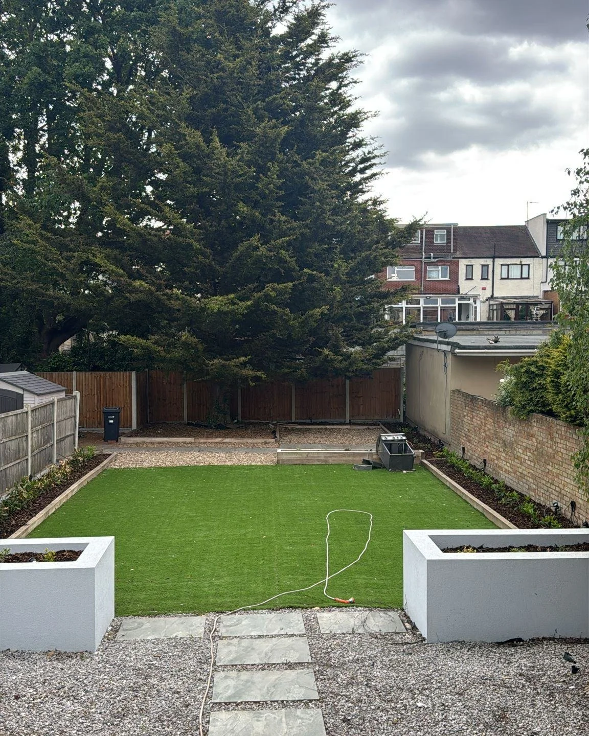 This is what happens when great design meets quality construction. 

This full garden renovation in London included custom composite raised planters, artificial lawn installation, slate stepping stone pathways, gravel landscaping, white render plante