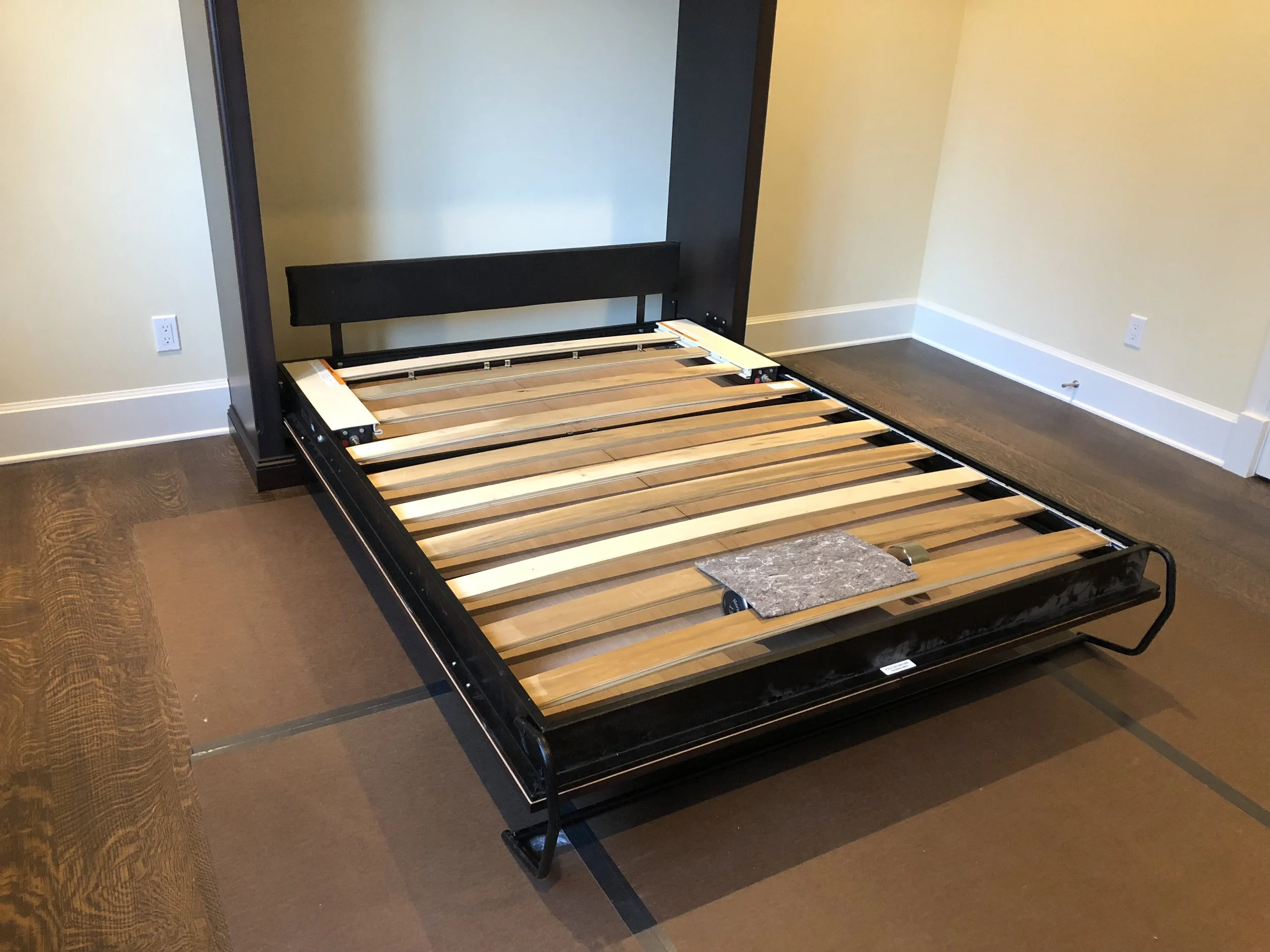 Murphy bed in open position with steel frame and wood slat base folding out from paneled cabinet—Noah & Noble, Greater Seattle.