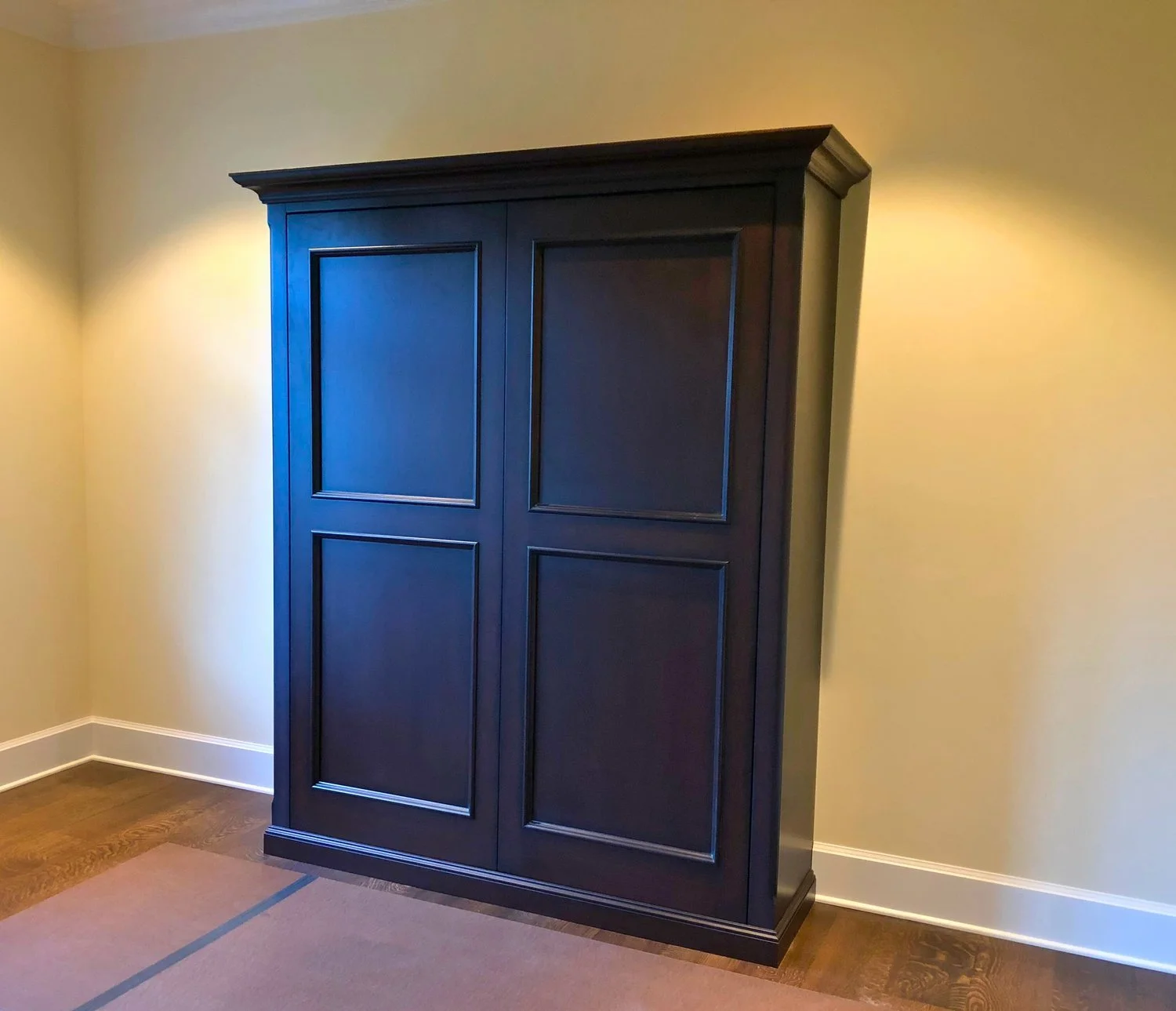 Custom Murphy bed cabinet with raised-panel doors, crown molding, and furniture-grade painted wood—Noah & Noble, Greater Seattle.