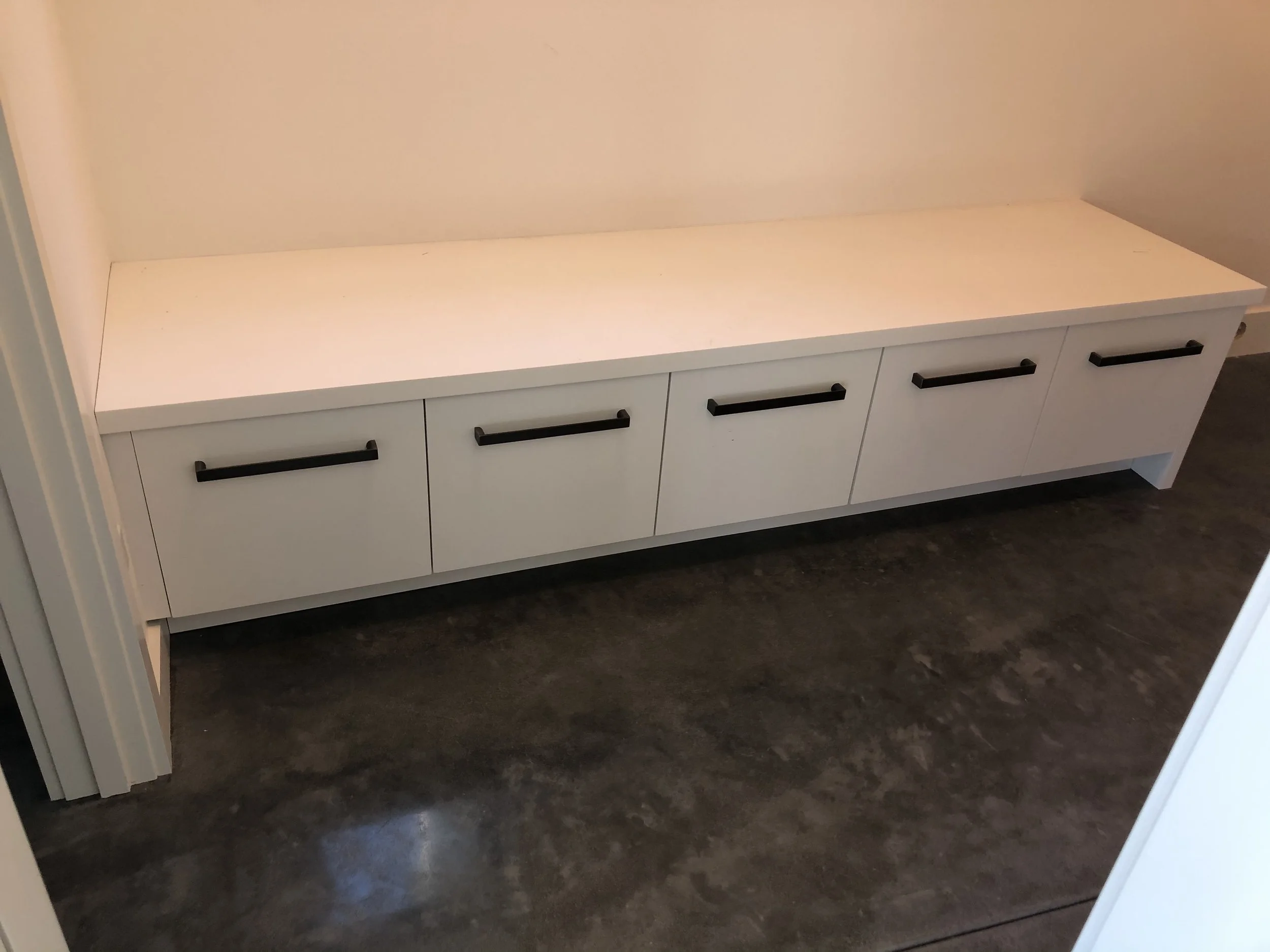 Modern built-in mudroom bench with five deep drawers, flat-panel fronts, and black hardware—Noah & Noble custom cabinetry.