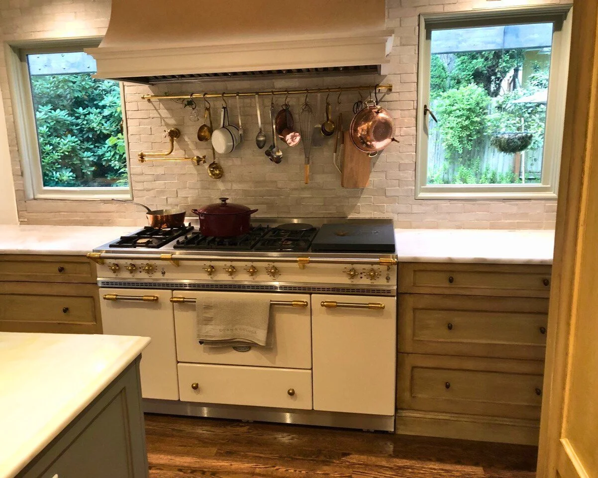 European-inspired range alcove with hanging cookware and shaker drawers—custom kitchen by Noah & Noble.