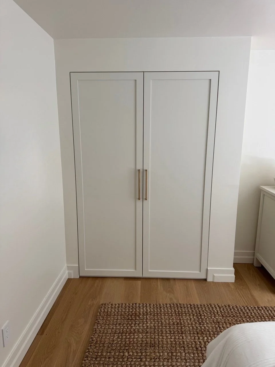 Custom bedroom closet with white shaker doors and long brass pulls—built-in wardrobe by Noah & Noble, Greater Seattle.