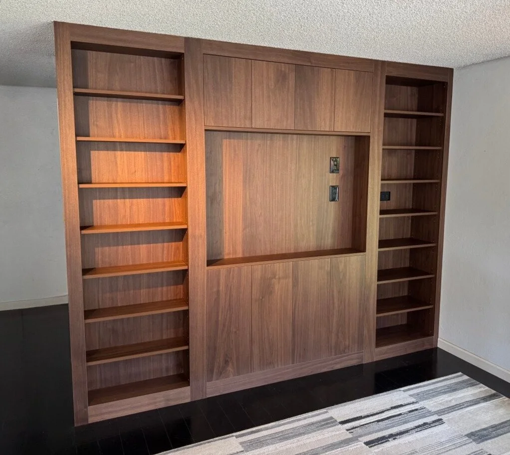 Custom walnut media wall with open bookshelves, slab panels, and a recessed TV niche with integrated A/V wiring—Noah & Noble, Greater Seattle.