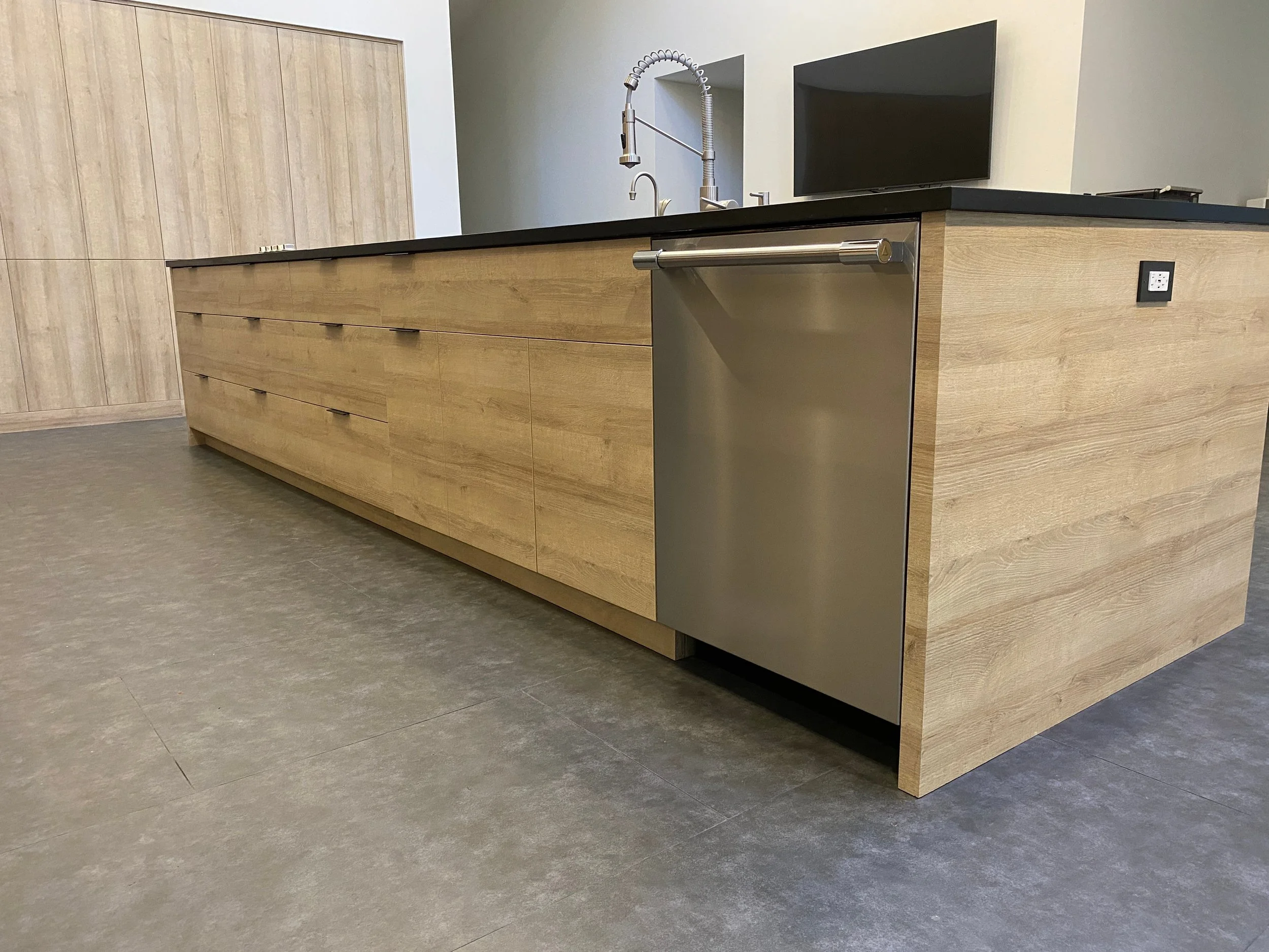 Long island run with deep drawer storage, integrated pulls, panel-ready dishwasher, and a Greenguard certified recycled Richlite countertop—Noah & Noble modern cabinetry.