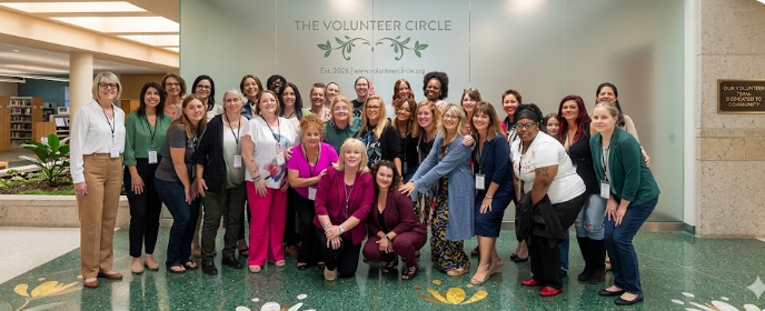 Group of diverse women standing together at The Volunteer Circle event in an indoor venue with a backdrop displaying the organization's name.