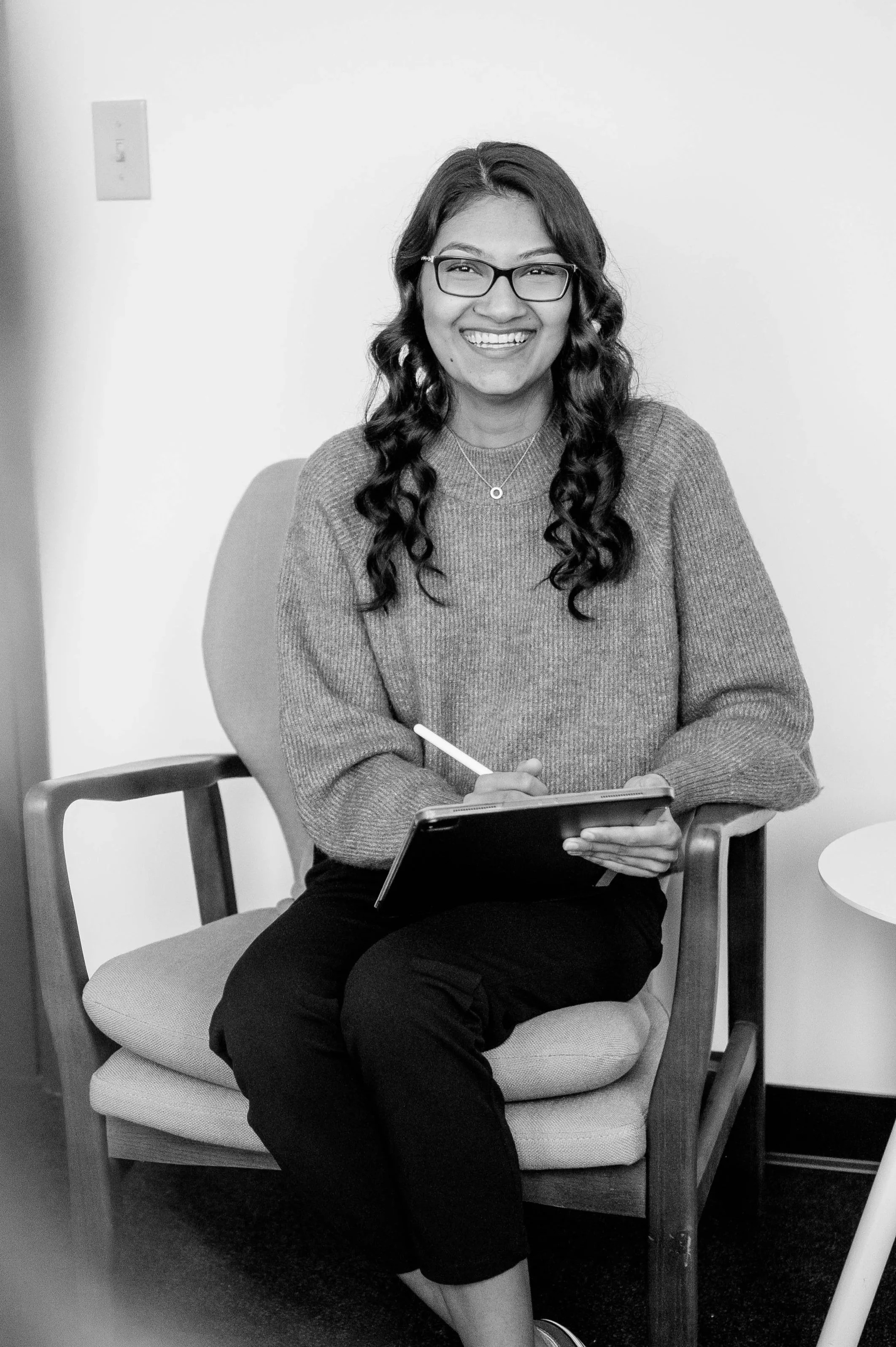 A kind woman, holding a tablet, sitting in a therapeutic space