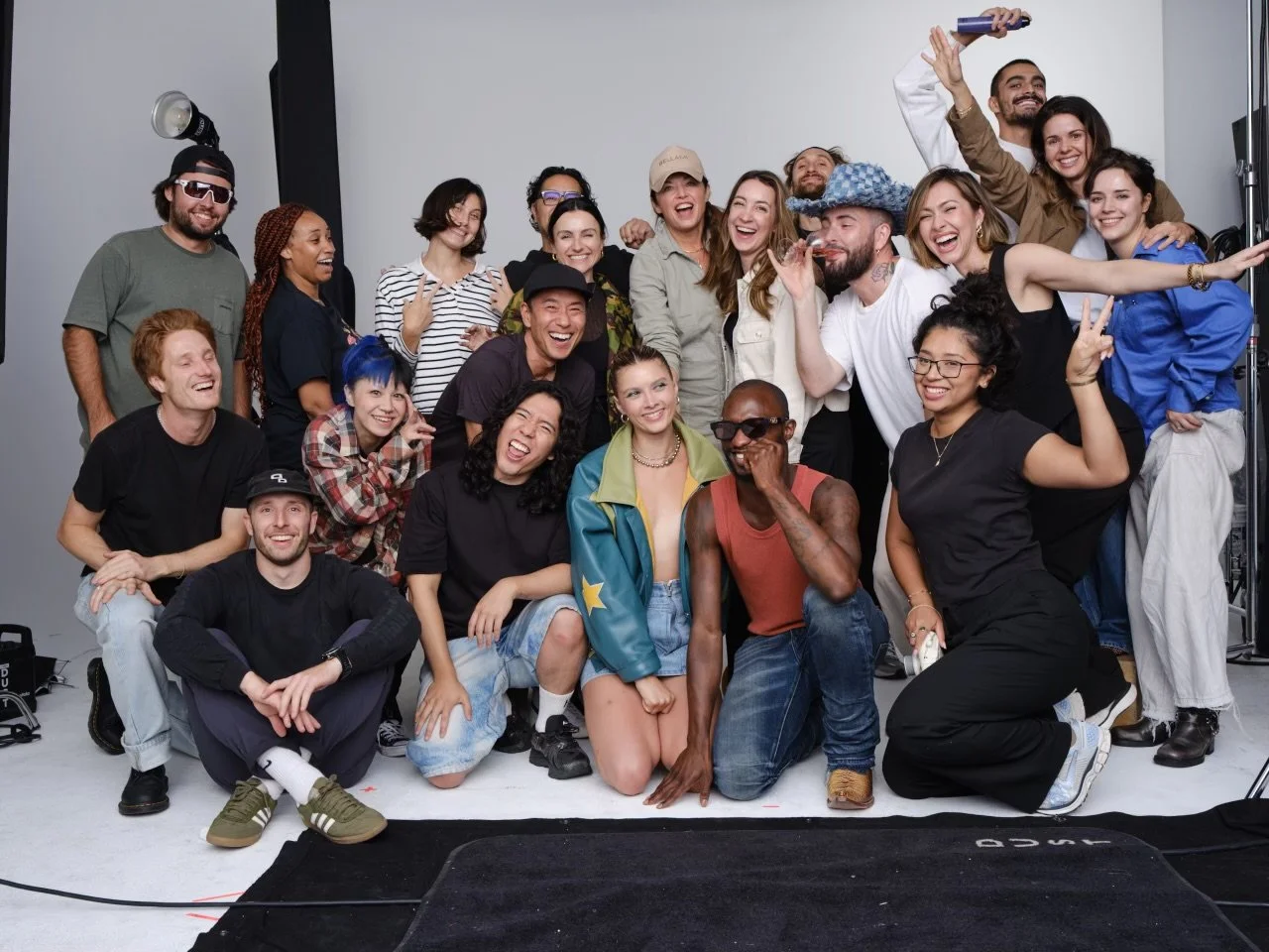 A large group of diverse people posing together and smiling for a photo in a photography studio including celebrity-stylist Andrew Fitzsimons.