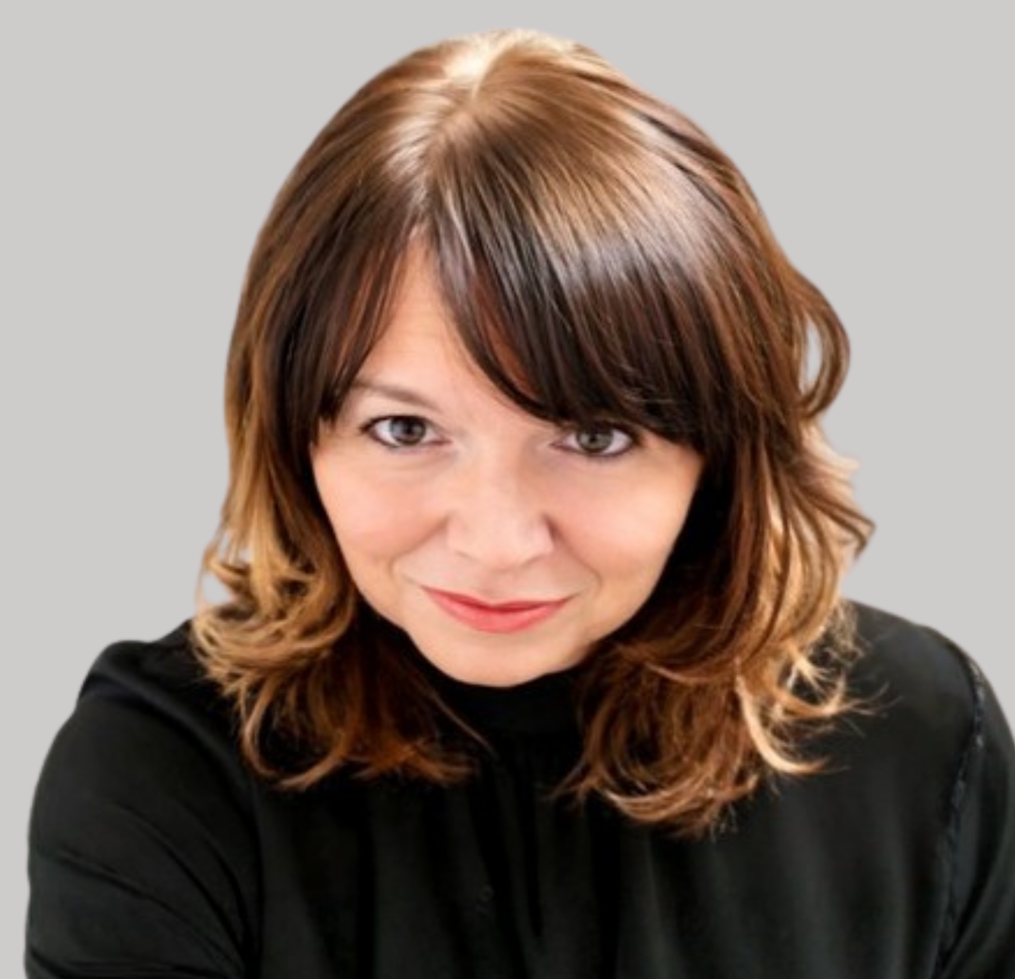 Smiling woman with shoulder‑length brown hair and lighter highlights, wearing a black top against a plain grey background.