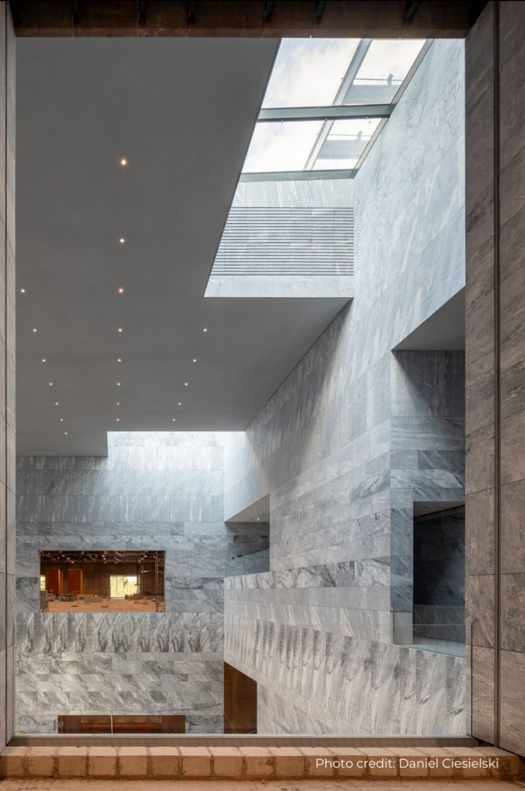 Interior view of a modern building with marble walls, a skylight, and ceiling lights.