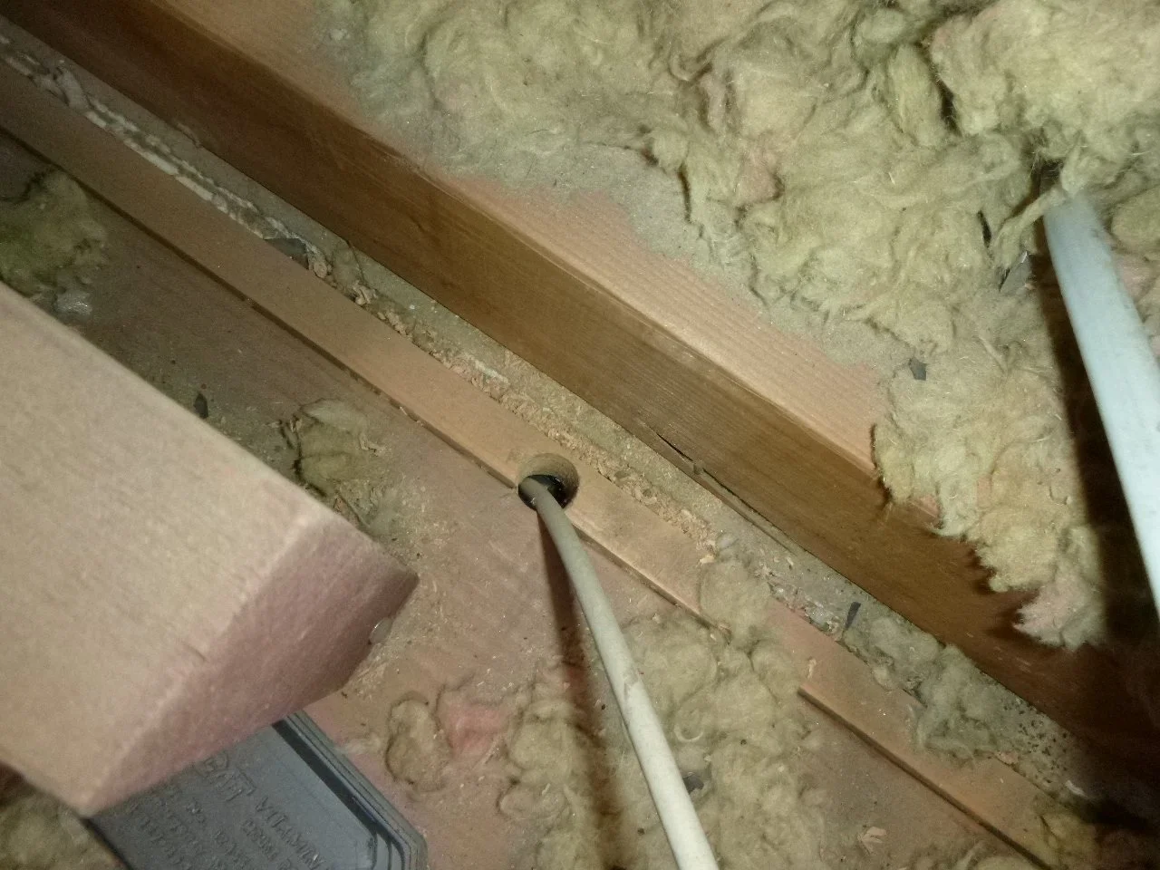 This is insufficient yellow loose-fill fiberglass. I prefer cellulose, but no matter what insulation you choose, it needs to be installed properly, fully and deeply, and in conjunction with proper air-sealing. (Note the unsealed wire penetration and