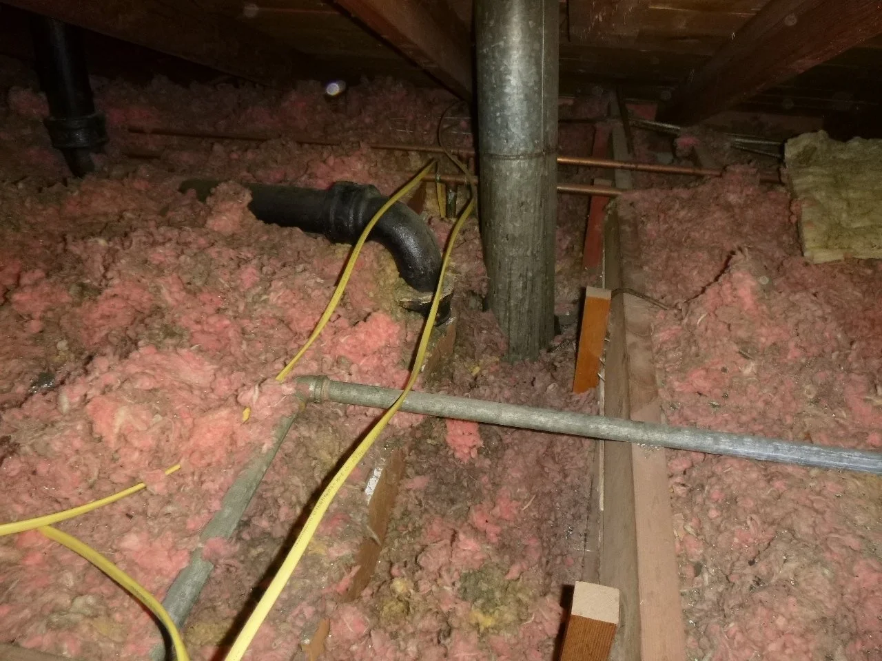 This is loose-fill pink fiberglass. Well, mostly pink. Note the discolored insulation around the exhaust duct and black pipe. That is a result of interior air moving into the attic, and vice versa. What good is a Yeti cooler if a dozen holes are dri