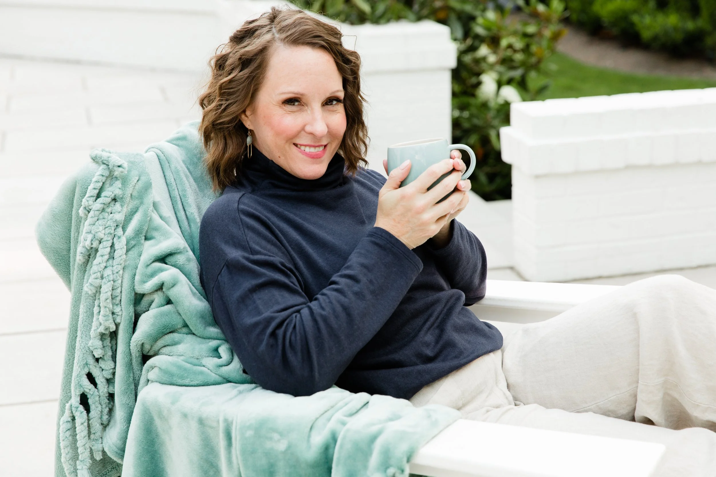Tammy Shultz seated comfortably outdoors holding a warm drink, representing her grounded and compassionate approach to functional nutritional therapy.