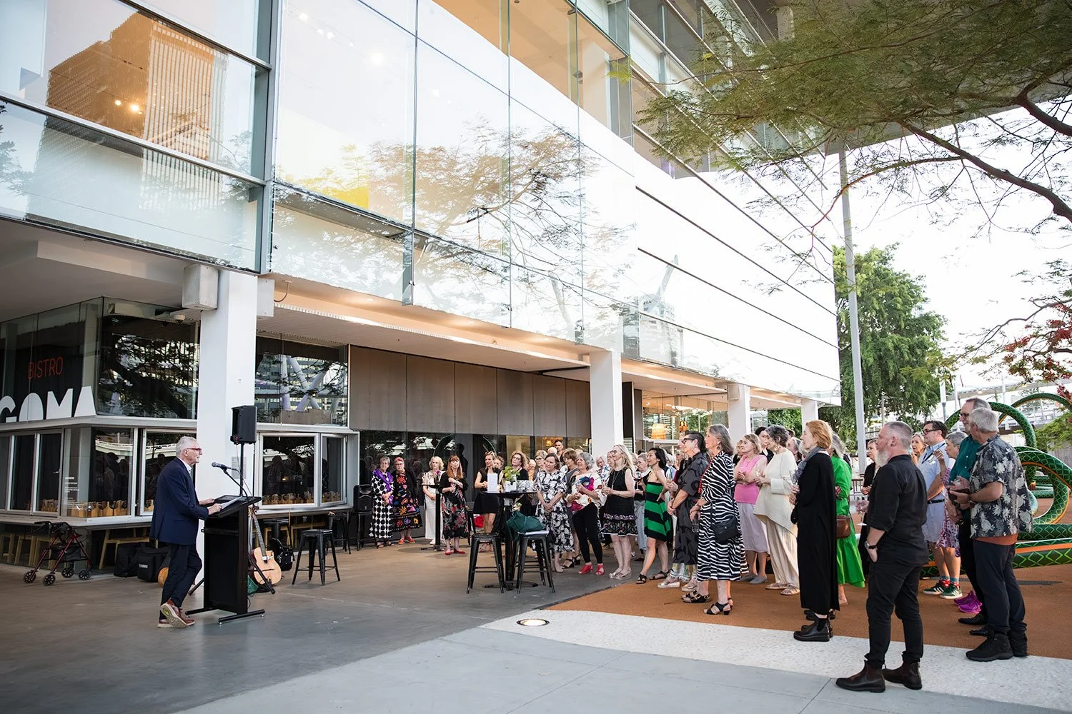 Wide view of presenter speaking to guests at outdoor GOMA event