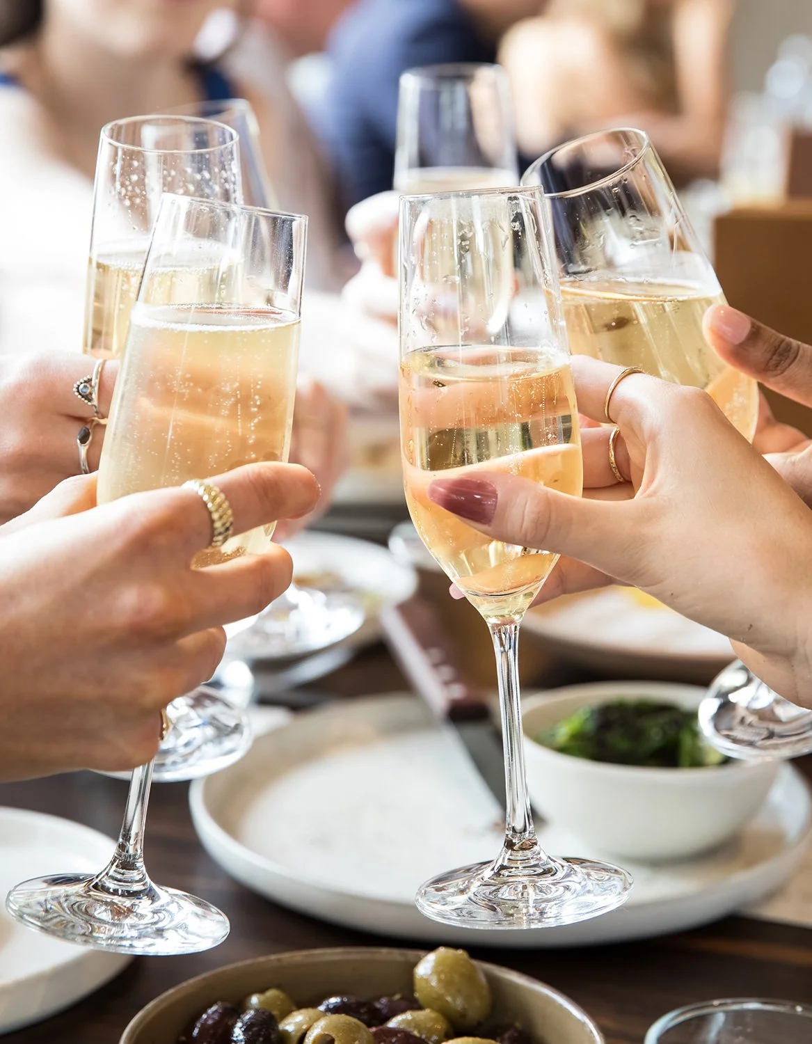Close up of six champagne glasses being clinked at a Brisbane lunch event