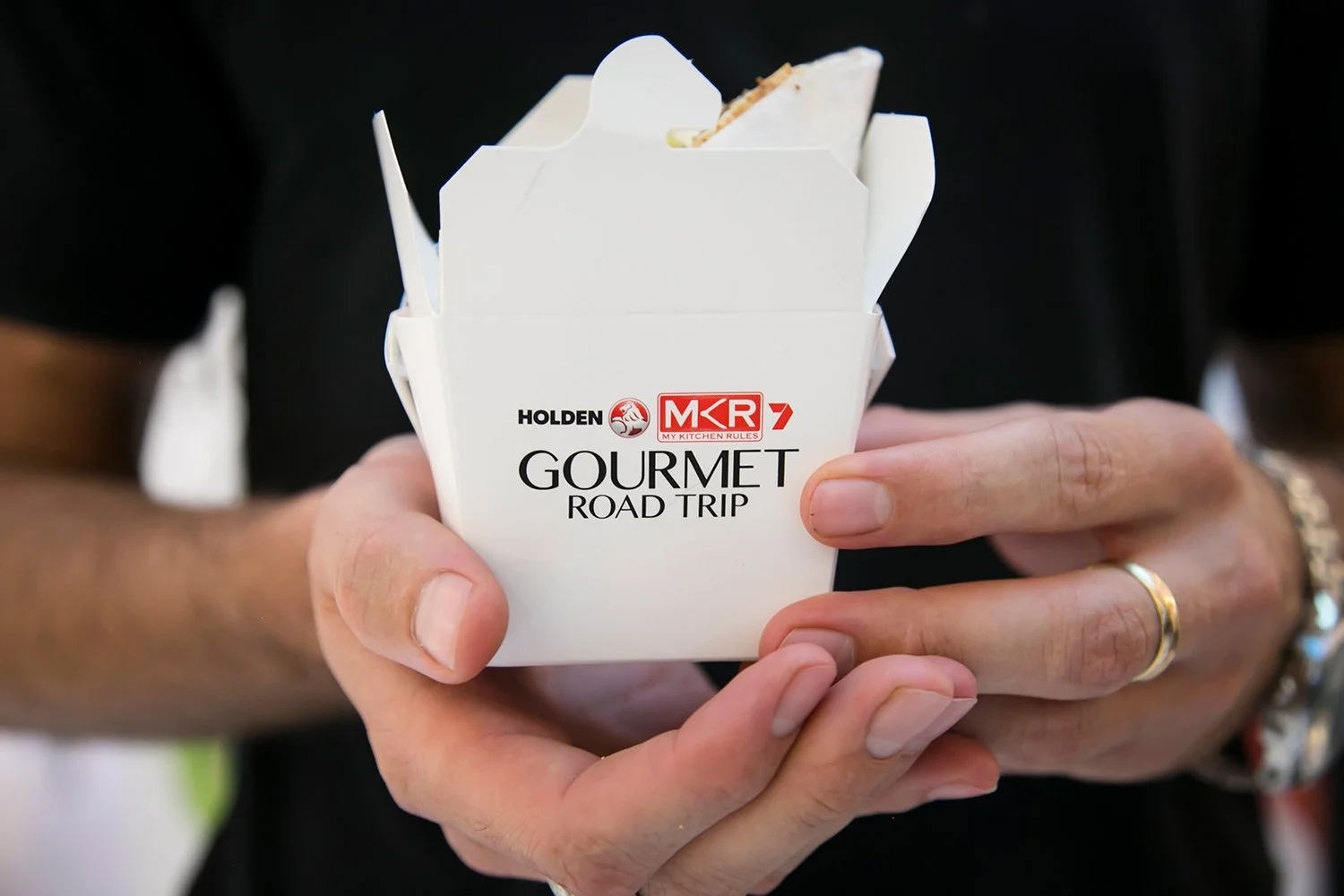 Hands holding branded food packaging at roadshow activation