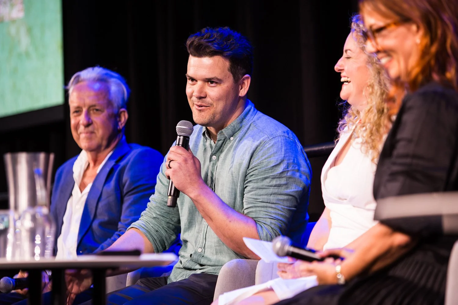 Four conference panelists laugh on stage during a funny moment at Sofitel Brisbane Central