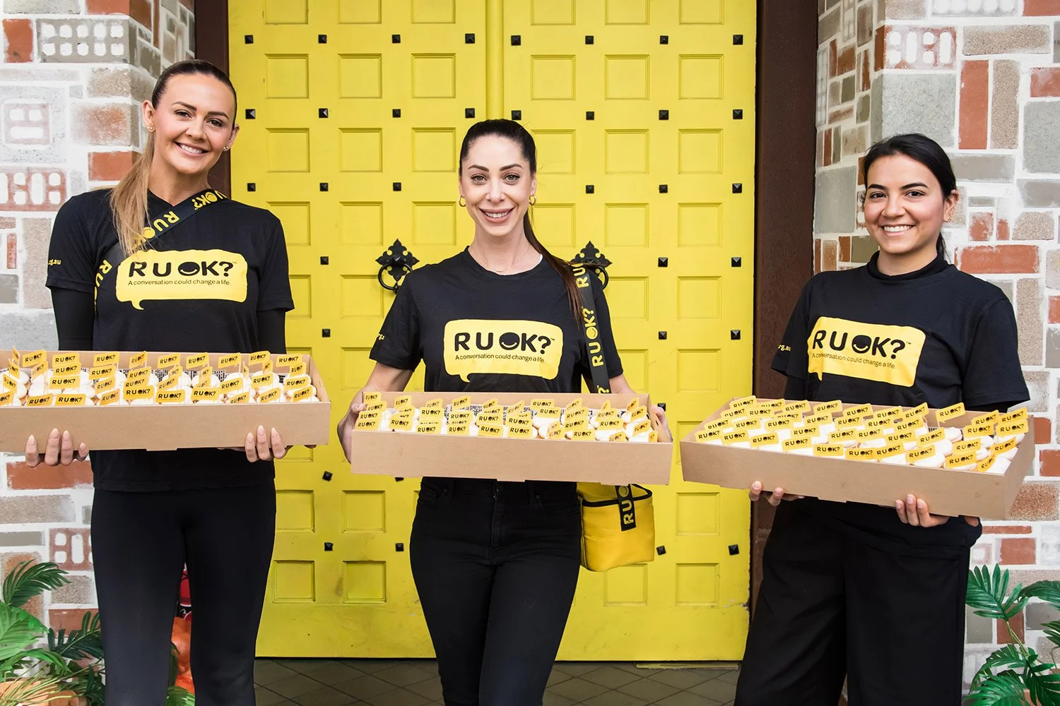 Promotional staff holding trays of branded cupcakes in Bowen Hills