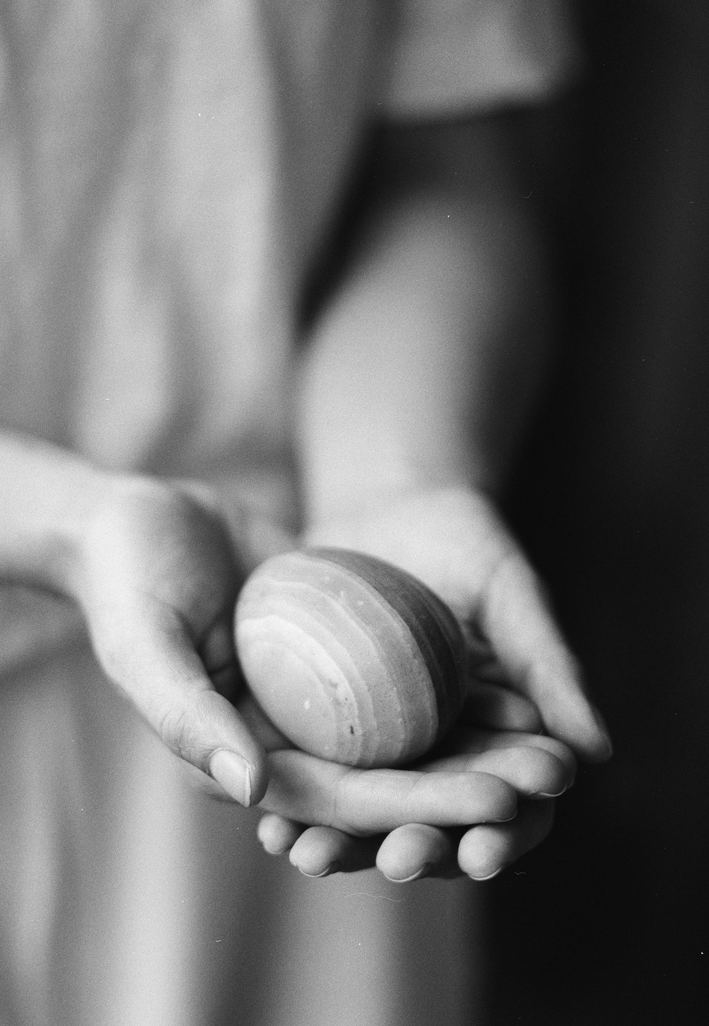 Close-up of a person's hand holding a small, rounded stone with concentric rings.