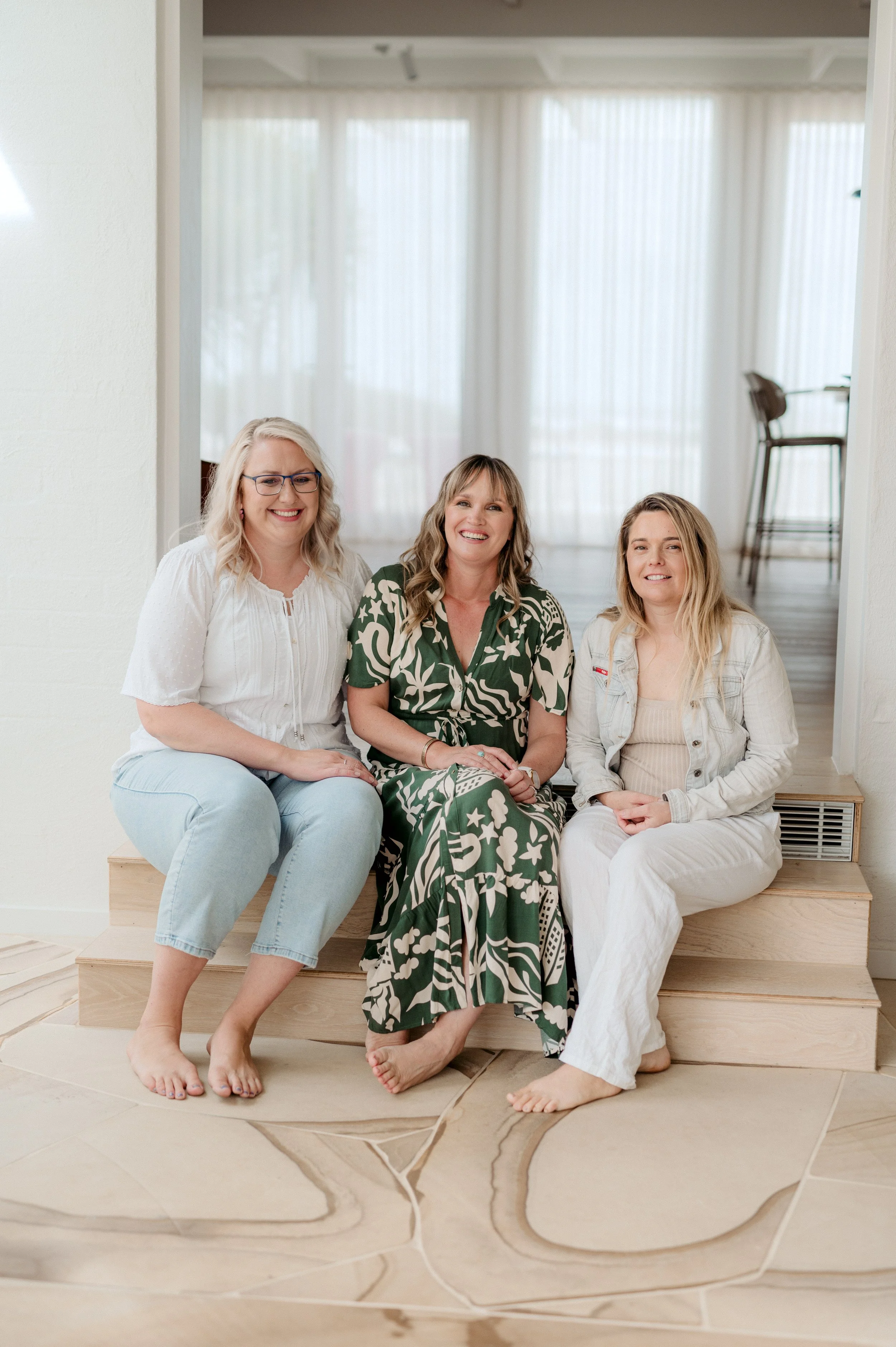 Three midwives sitting on step smiling