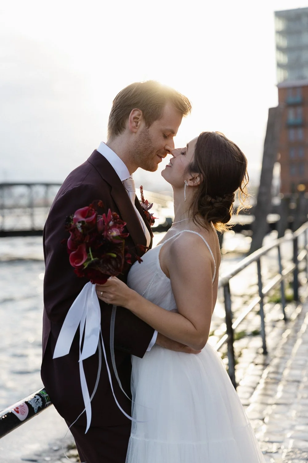 Romantic couple kiss at sunset during wedding photos in Hamburg harbor