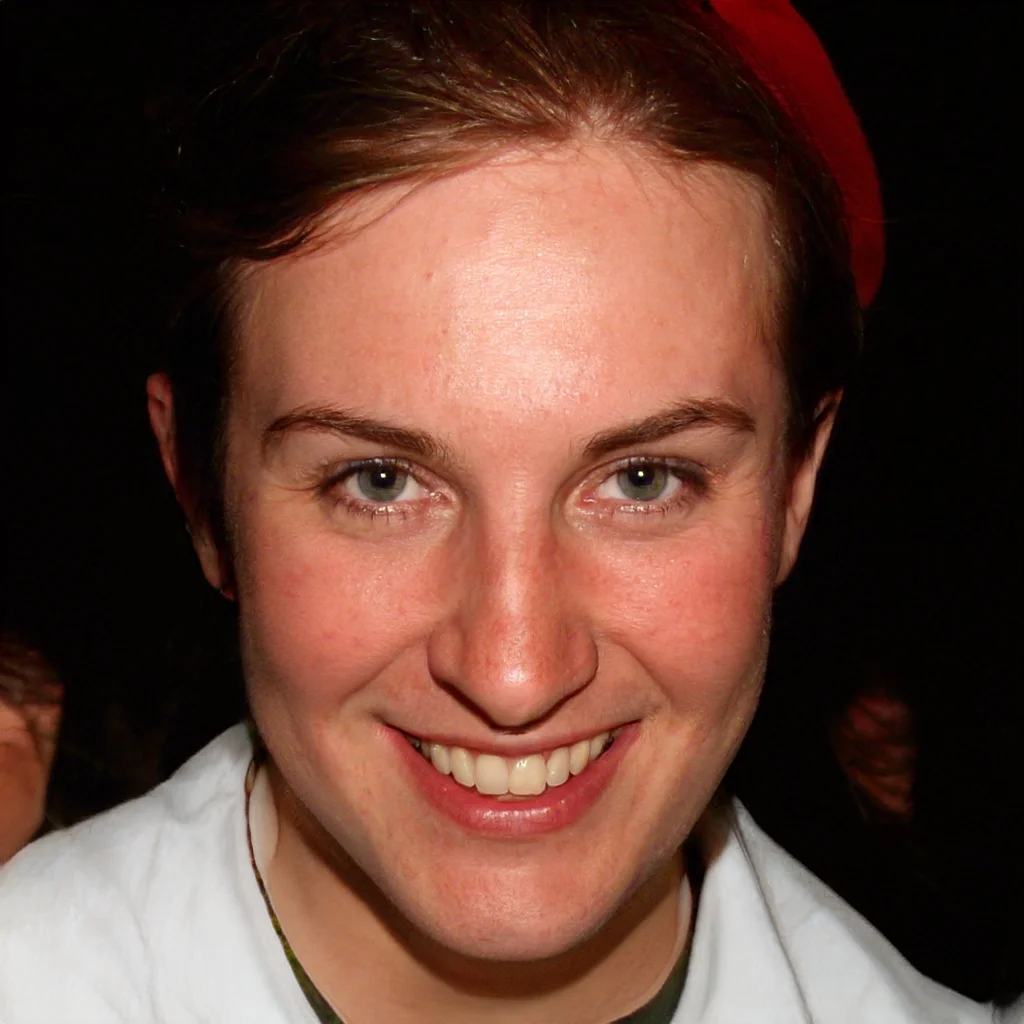 Close-up of a smiling woman with short brown hair and light skin, wearing a red beret and a white top.
