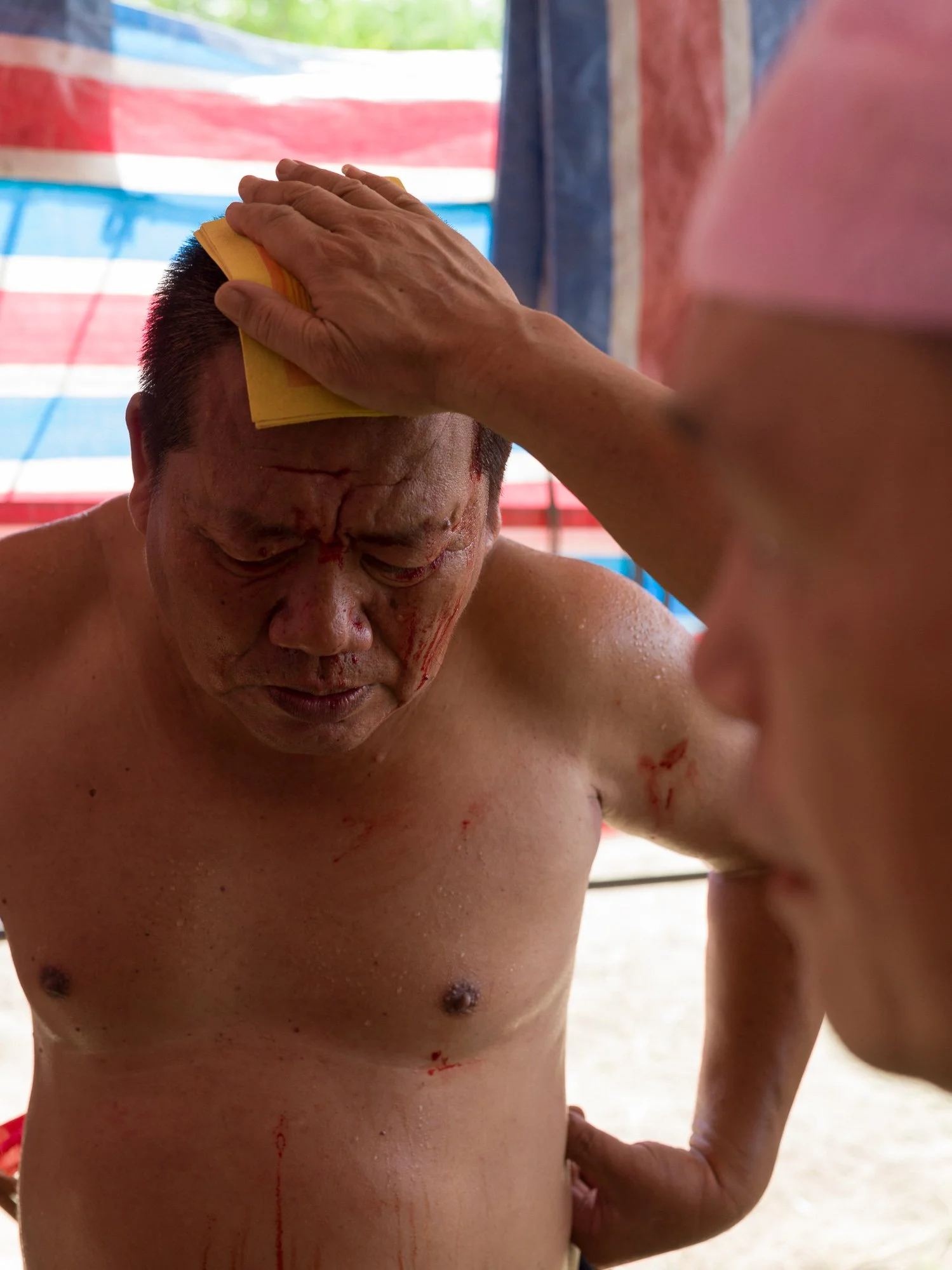 A Tâng-ki (spirit medium)  sheds blood to enter a trance, enabling divine communication during a traditional ritual.
 Sai-káng, Tainan, Taiwan 2022.