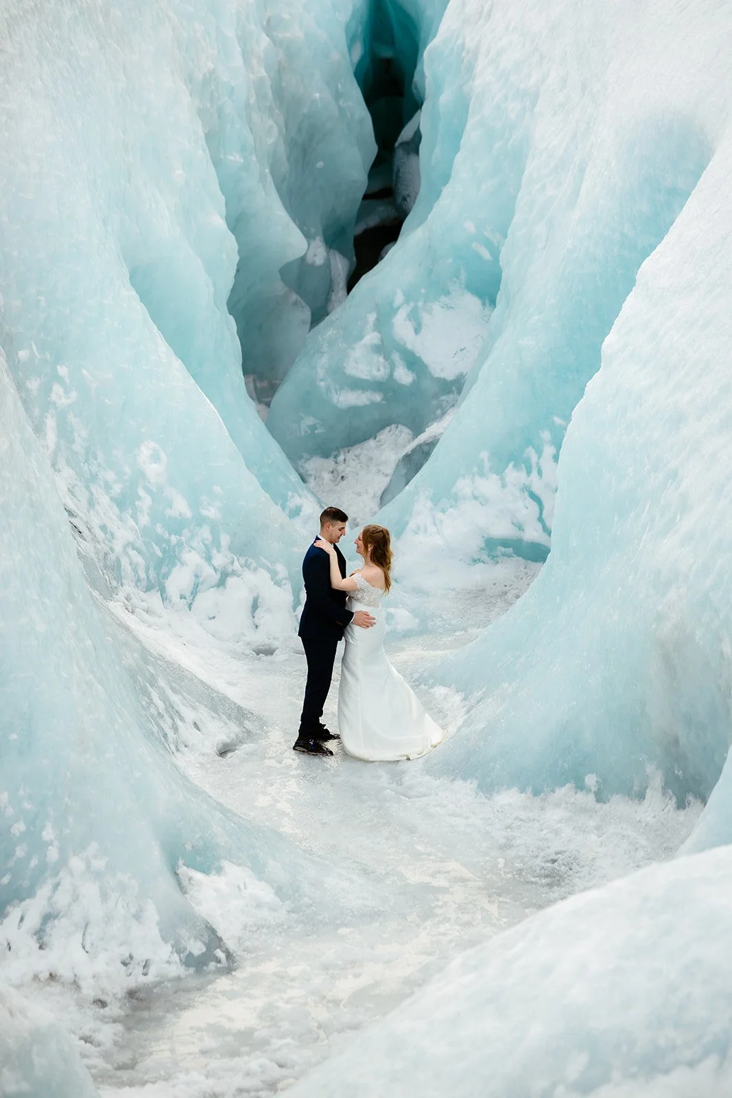 bride and groom stand in glacier ice cave while taking iceland elopement photos