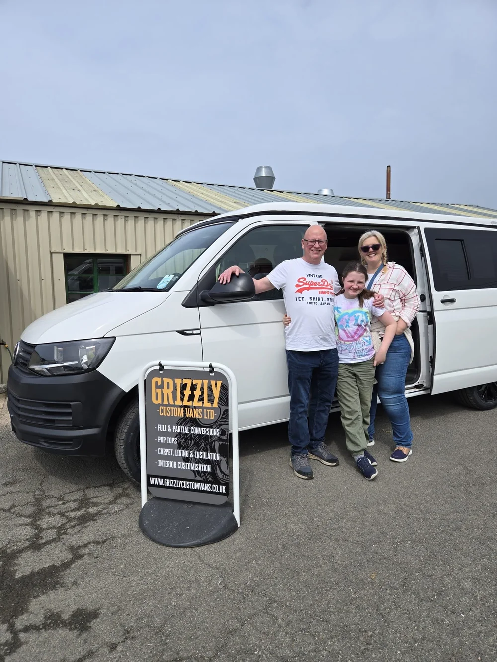 Family of three standing beside their VW T6.1 camper conversion built by Grizzly Custom Vans