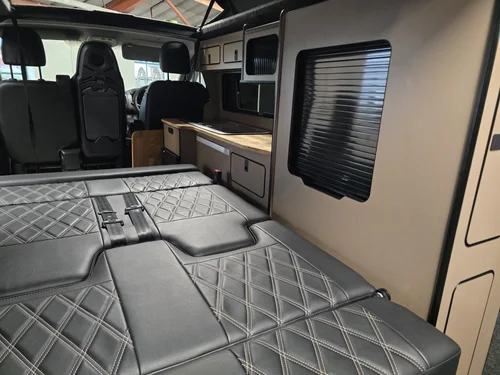 Rock and roll bed inside the Fiat Talento camper conversion featuring diamond stitched upholstery.