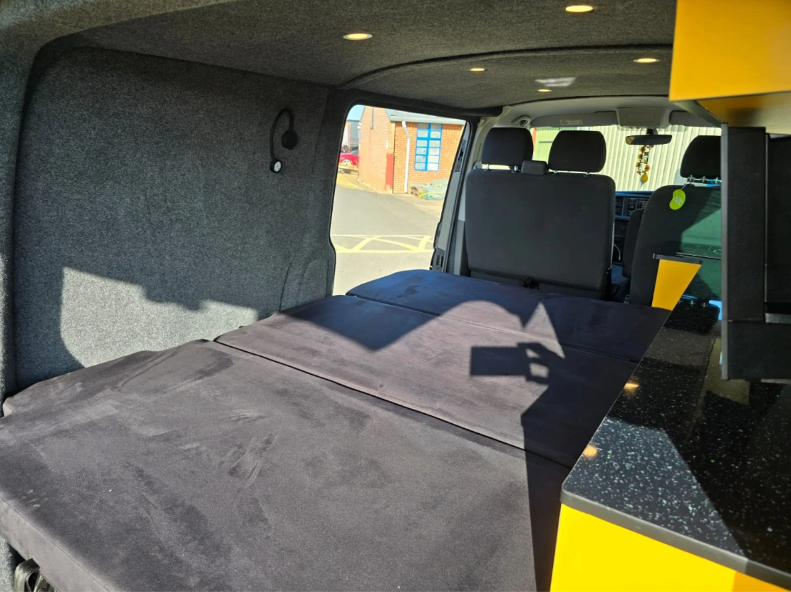 Three-seater bed layout providing flexible seating and sleeping in a VW T6.1 camper conversion
