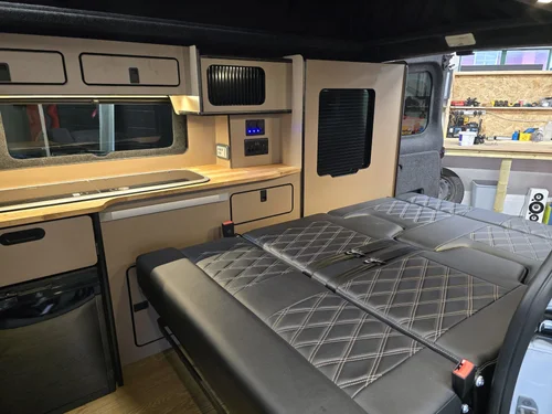 Under-bed storage area with integrated lighting inside the Fiat Talento camper conversion.