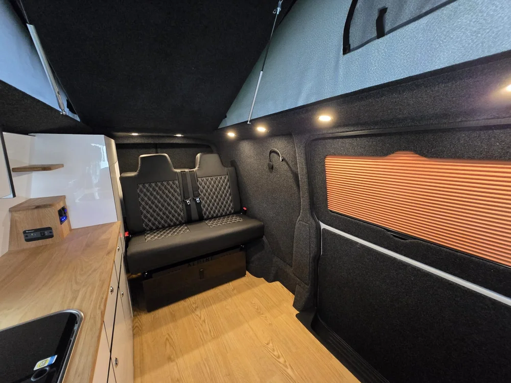 Rock and roll bed with white diamond stitching inside a VW T6.1 camper conversion