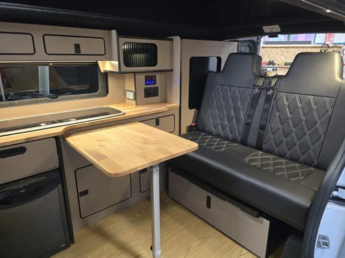 Fold-out dining table and seating area inside the custom Fiat Talento camper conversion.