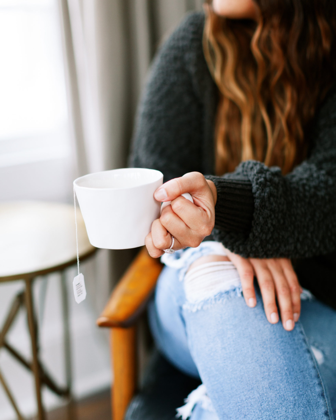 Woman sitting with a coffee mug, reflecting on mindset shifts for solo entrepreneurs building a brand.