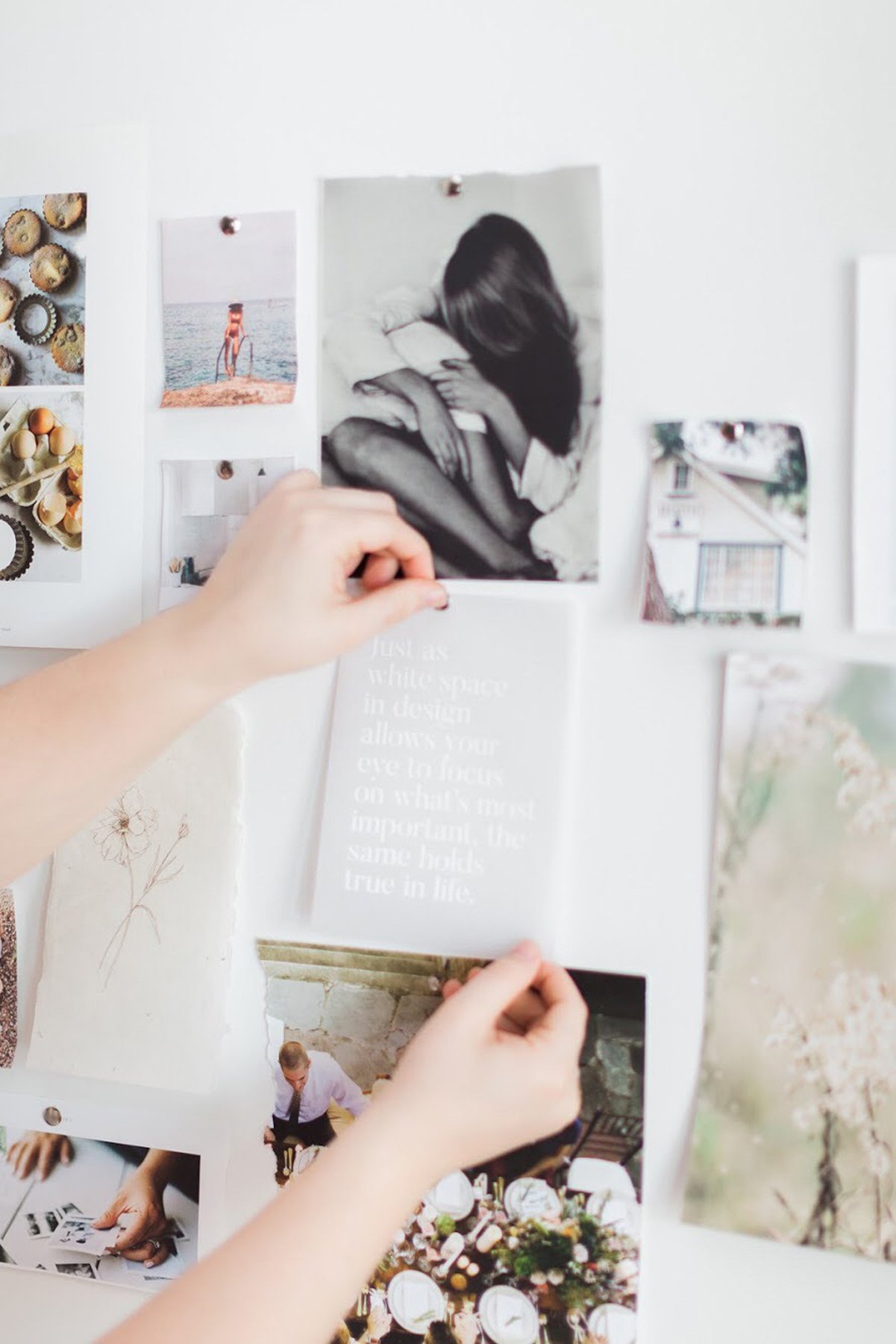 Hands arranging photos on a vision board, defining the pillars of a DIY branding system.