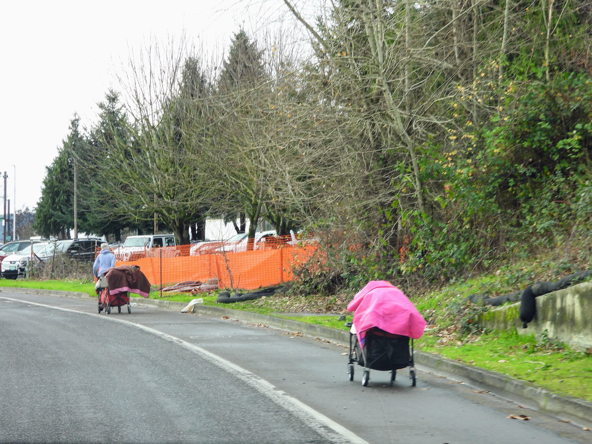   Een zwerver die eerst het ene karretje verplaatst en dan de volgende weer ophaalt  