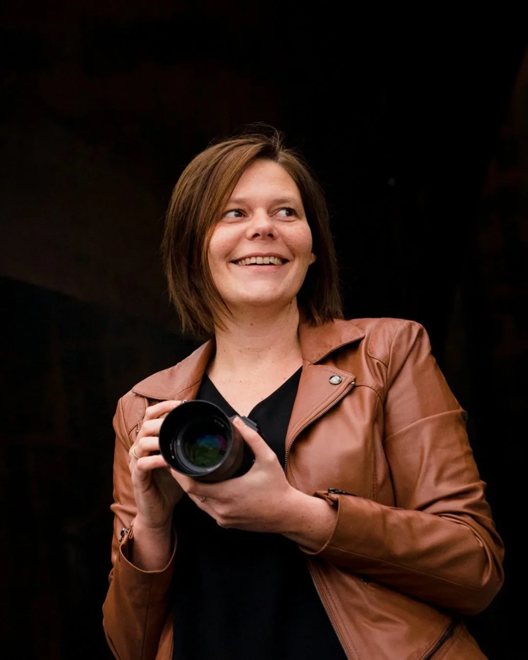 Nathalie Moors, hondenfotograaf van studio oh my dog, lacht terwijl ze haar fototoestel vasthoudt