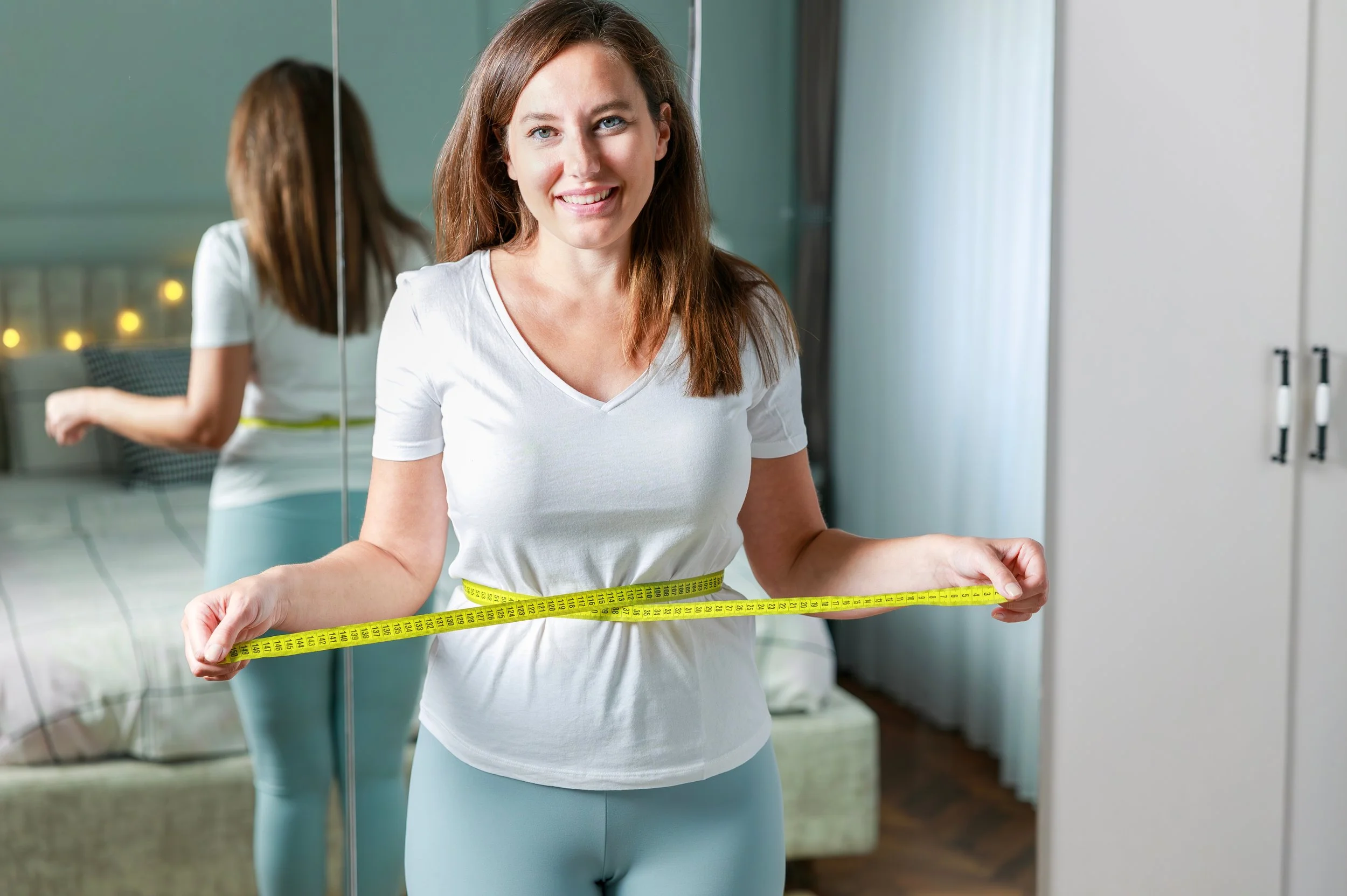 Woman holding measuring tape around her waist