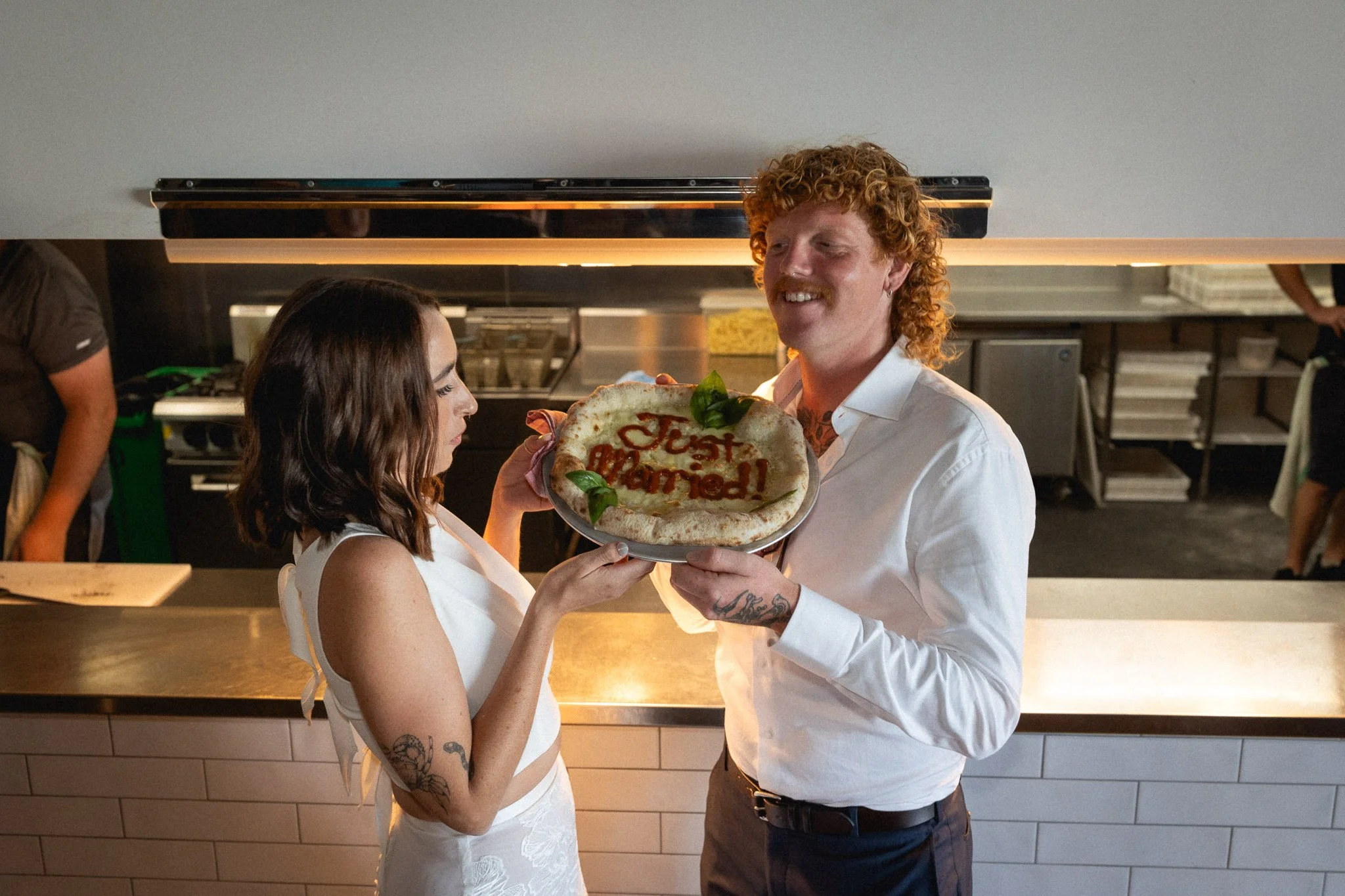 couple holding a pizza with just married written on it