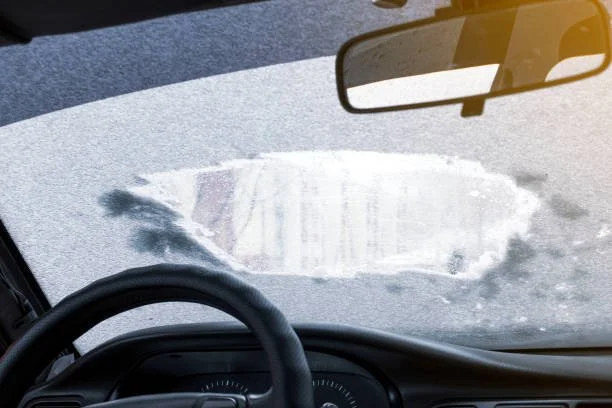 Frost-covered car windshield with a cleared patch
