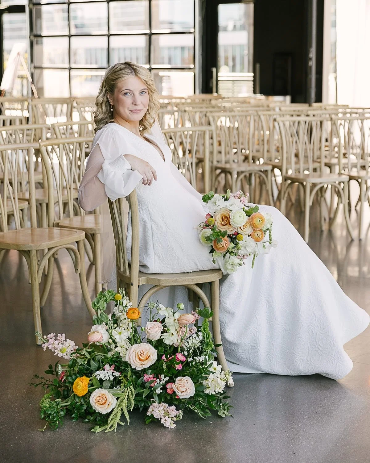 An outdoor dining table decorated with flowers, candles, and candles in front of a large leafy tree, with string lights overhead.