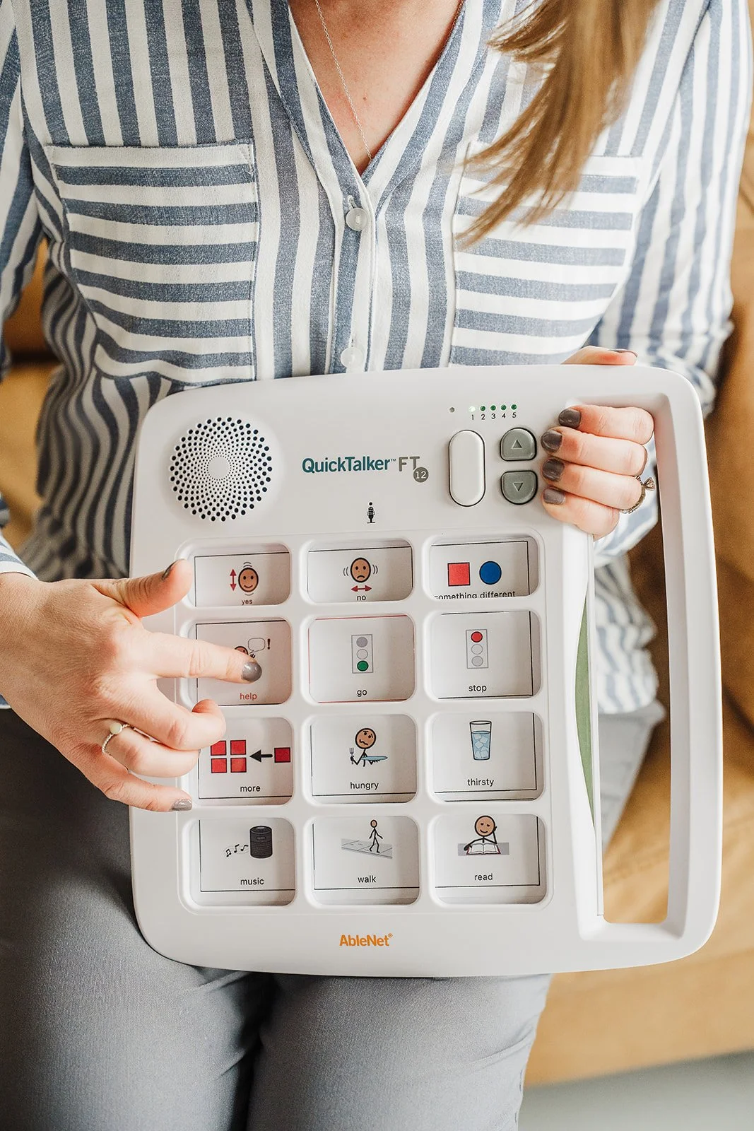 A person pointing to the message "help" on a mid-tech AAC device