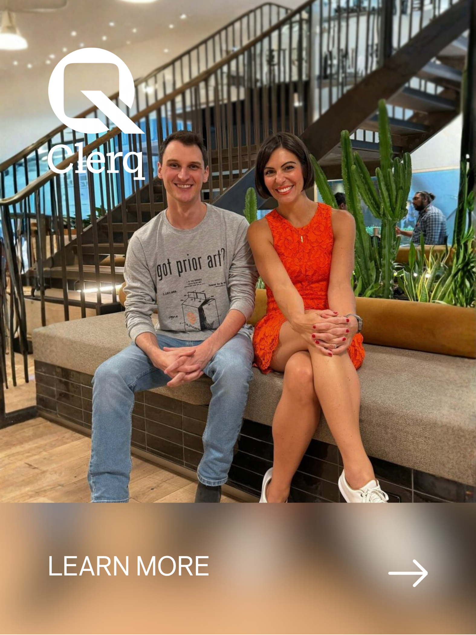 Two people sitting on a bench in a restaurant or cafe with plants behind them. The person on the left is a man wearing a grey sweatshirt and jeans, and the person on the right is a woman wearing an orange dress and white shoes. There is a logo and te
