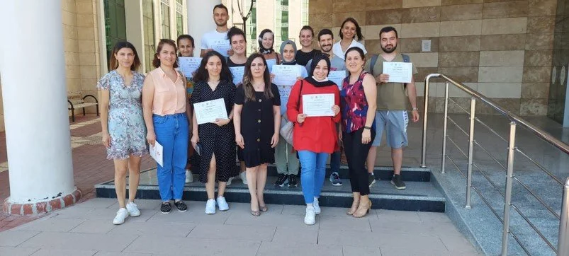 Group of young adults standing outside a building, holding certificates, celebrating achievement.