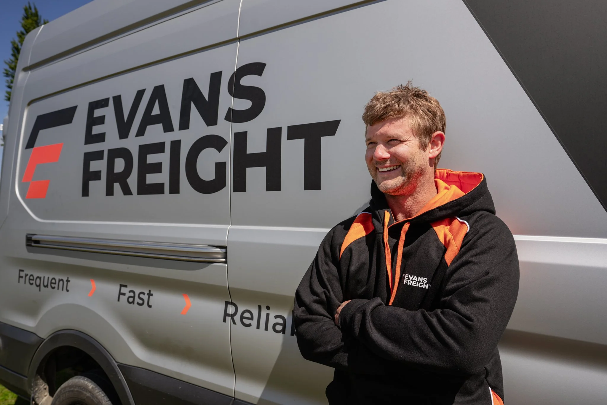 Evans Freight team member smiling in front of an Evans Freight delivery van in Te Anau, Southland, New Zealand, representing the friendly local freight service trusted by the Southland community.
