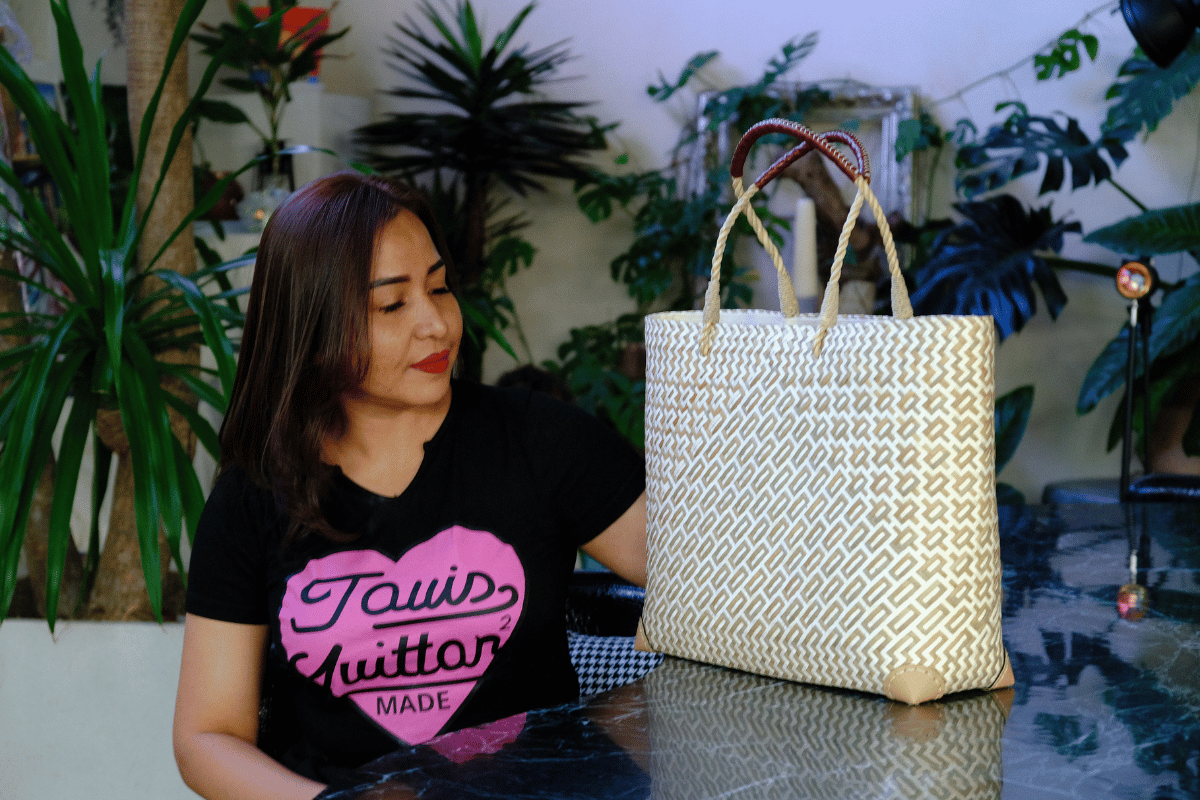 Model sits beside the Na Nu Geometric Tote, contrasting artisan craftsmanship with contemporary streetwear for a playful lifestyle moment.