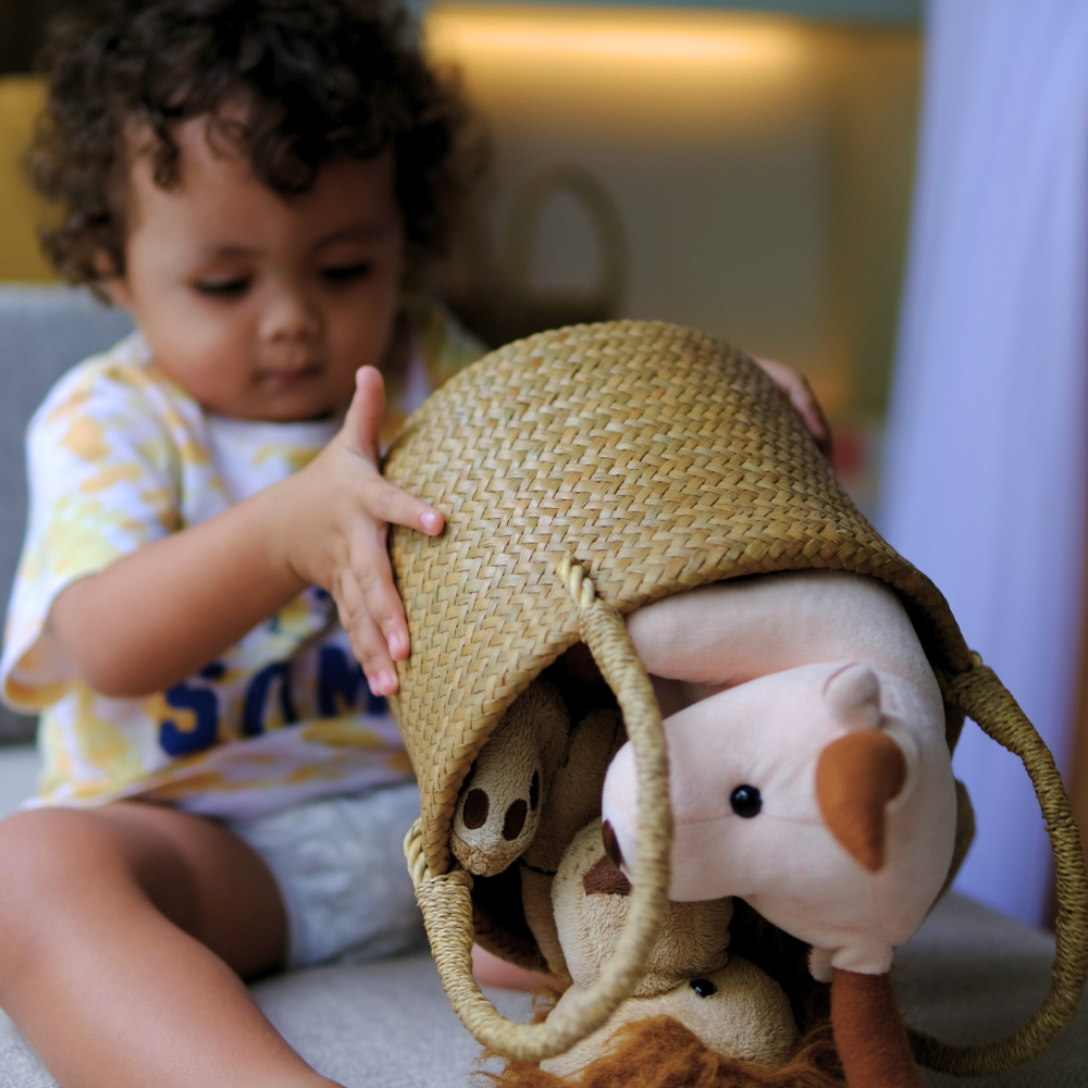 A young child engaging with the Tung Dek basket, tipping out stuffed animals—capturing its playful utility and child-friendly size.
