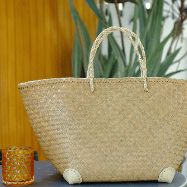 Rewadee bag displayed on an indoor wooden table next to a candle and plant, suggesting natural charm in modern interiors.